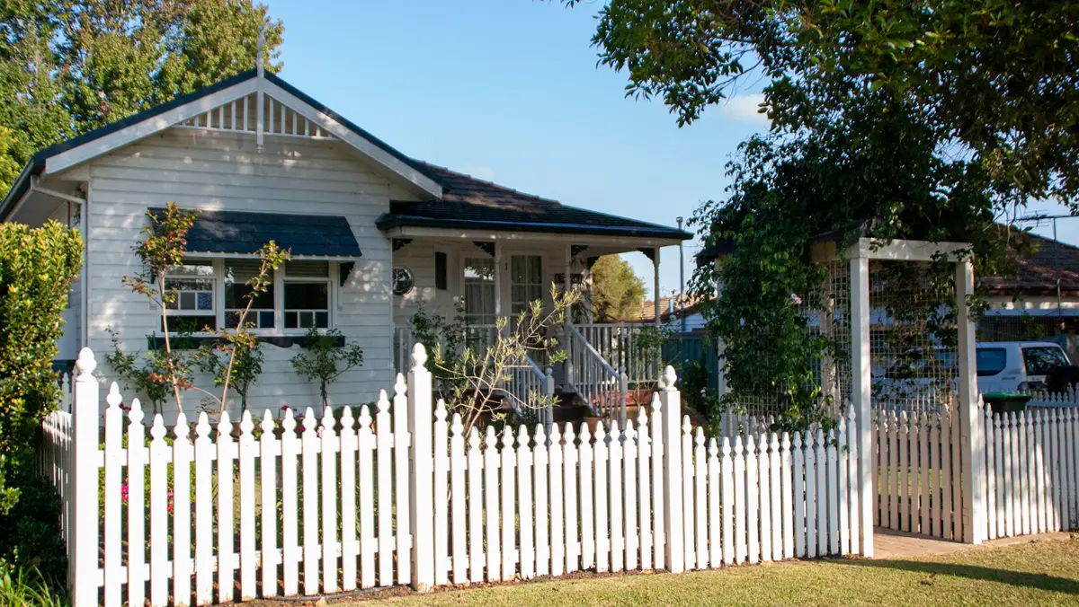 Fibro-clad house behind a white picket fence