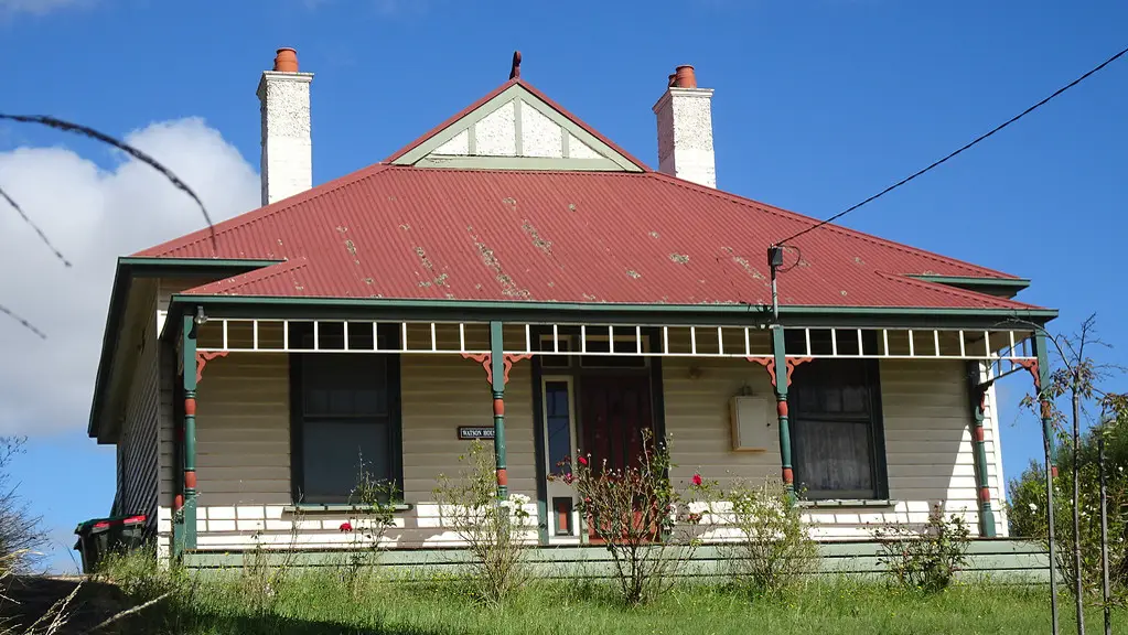 Weatherboard cottage with a red iron roof, twin chimneys and a front verandah